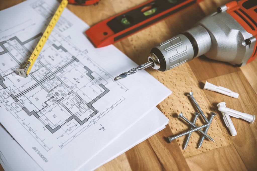 Home Building Plans with wall anchors/screws, drill, level, and measuring tape for precise installation.