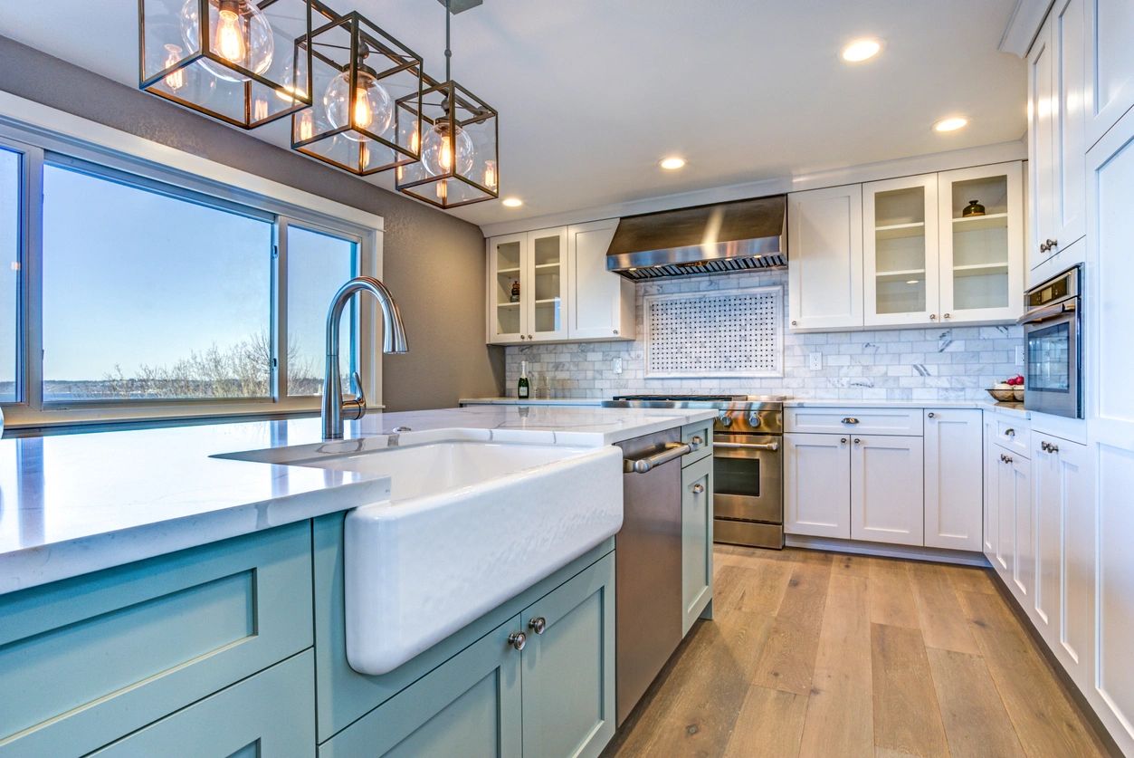 Modern Farmhouse Kitchen with white cabinetry, teal island, wood floors, quartz countertops, and quartz backsplash.