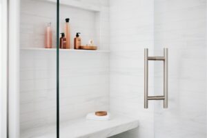 A contemporary bathroom featuring a glass shower door and a shower bench inside.